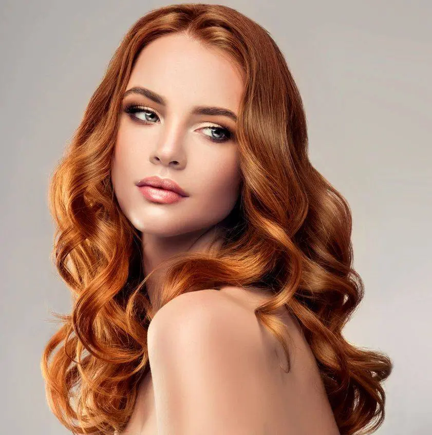 Red haired woman with voluminous, shiny and curly hairstyle.Flying hair